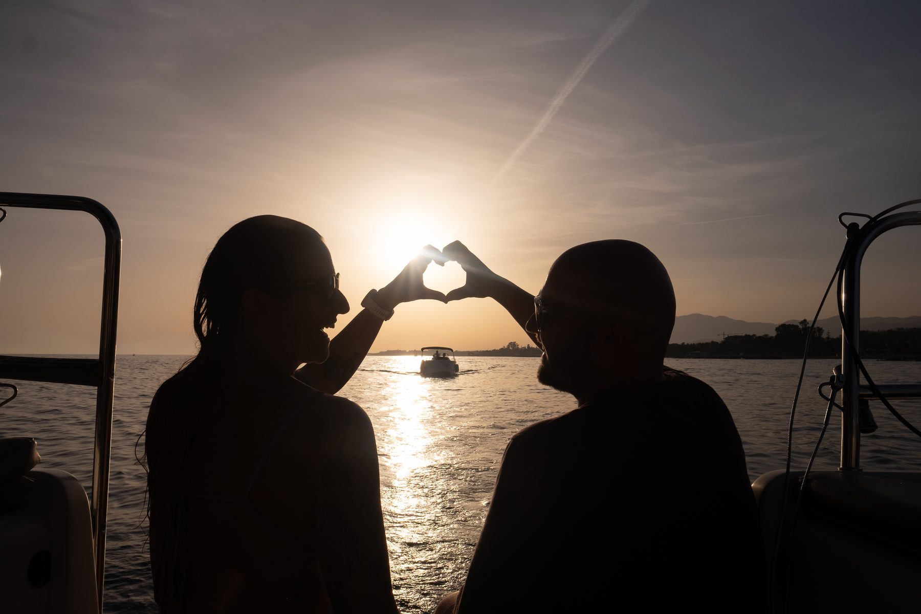 Couple forming a heart shape at sunset on a sailing trip off Marbella